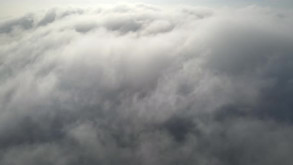 Aerial shot of flying over a layer of soft clouds at dawn