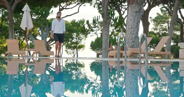 Man Walks Along a Pool in Isolated Seaside Resort