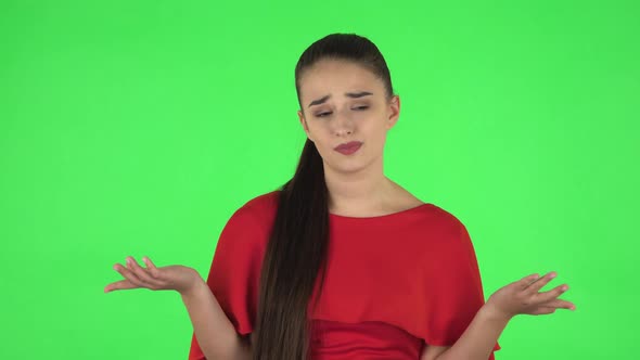Portrait of Pretty Young Woman Is Upset Is Shrugging and Sighing. Green Screen