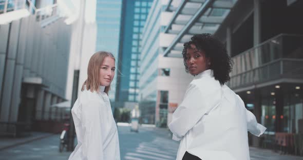 Two young women in business attire, with a bike in a business area