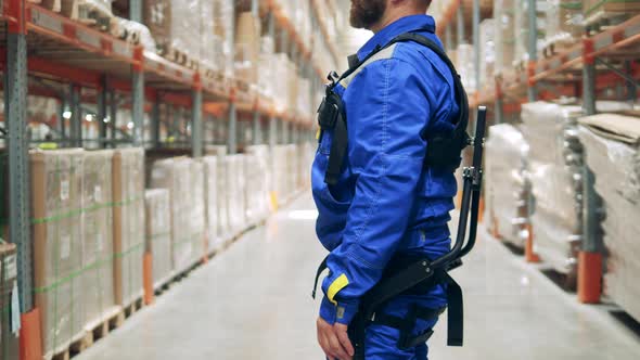 Warehouse with a Male Specialist Wearing Exoskeleton