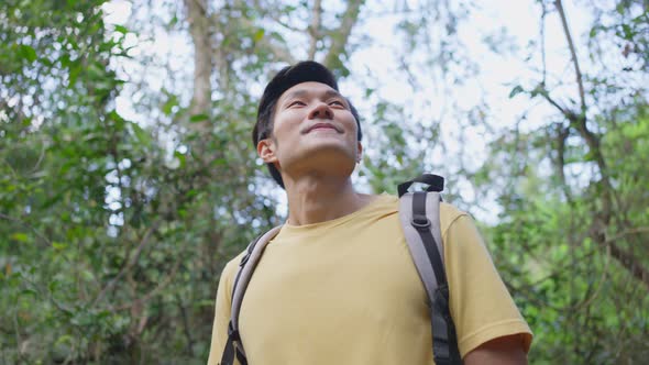 Young Asian man traveling in the forest alone feel exciting and relax in nature wild with happiness.