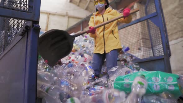 Footage of a Young Woman in Yellow Jacket and Gloves Scoops Using Shovel Used Plastic Bottles at