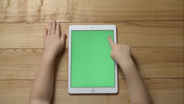 Young Girl Using a Tablet Sitting On a Wooden