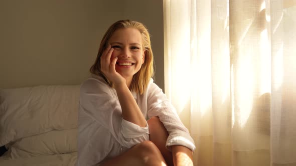 Blonde Woman Posing by the Bedroom Window with Sun Beaming on Her Skin