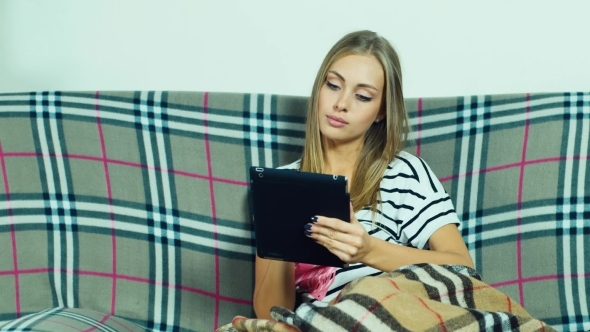 Blonde Sits On The Couch And Works With Tablet