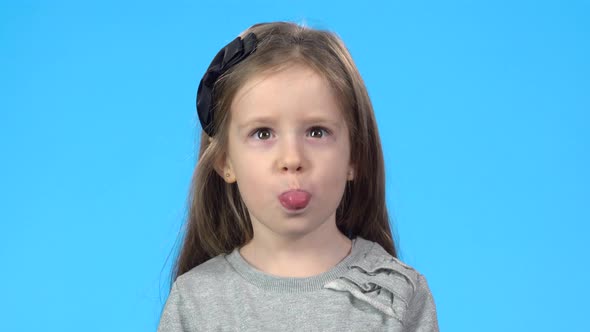 Little Blonde Girl Is Showing Her Tongue and Making Faces