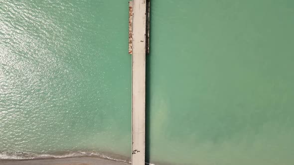 Sea with a Concrete Long Pier in the Spring with People Filmed on a Drone