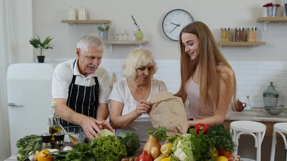 Elderly Couple in Kitchen Receiving Vegetables From Grandchild. Raw Food Healthy Eating Diet