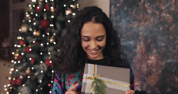 Happy Pretty Girl with Beaming Smile, Holding Nice Wraped Present Box in Her Hands and Showing To