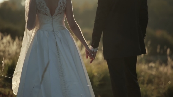 Young Bride And Groom At Sunset Holding Hands