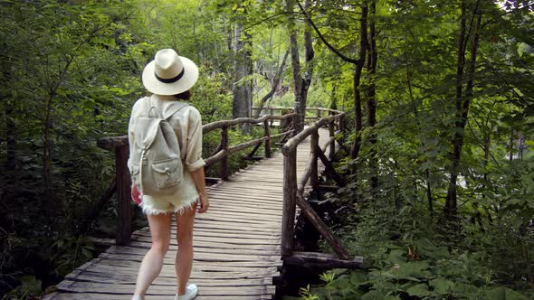 A young girl in shorts walking on a wooden bridge in a national park