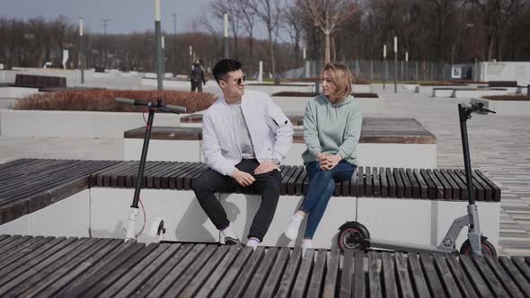 A Man and a Woman are Sitting on a Bench and Have a Conversation