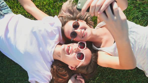 Young Happy Caucasian Women Lying on Grass and Filming Themselves on Phone