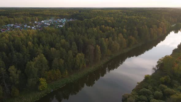 Flight on a Quadcopter Over a Calm River at Sunset and Forest