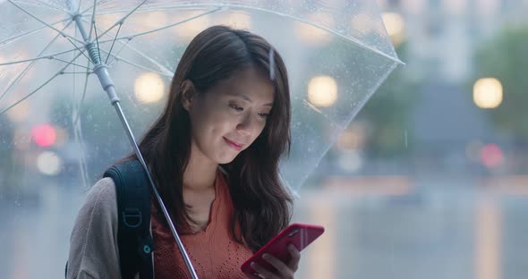 Woman use of mobile phone and hold with umbrella in the evening