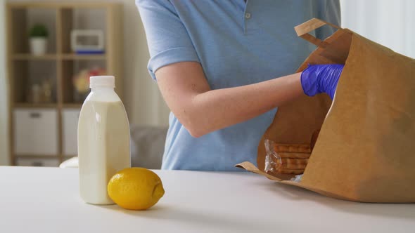 Woman in Gloves Taking Food From Paper Bag at Home