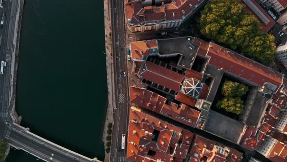 Top down drone shot over red rooftops European City at sunset along a blue river Lyon France