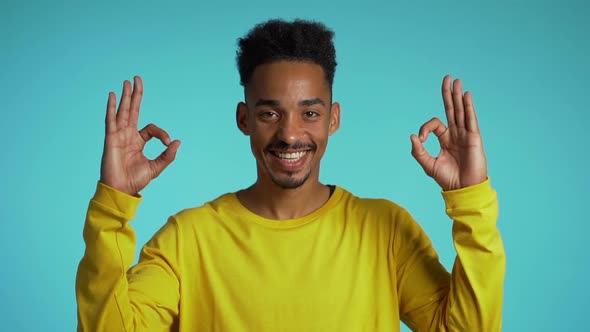 Positive young african guy smiles to camera. Young man making OK sign