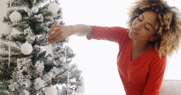 Pretty Young African Woman Decorating An Xmas Tree