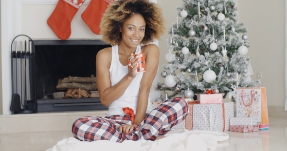 Smiling Young Woman Enjoying a Cup Of Xmas Coffee