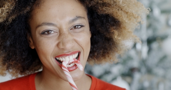 Fun Young Woman Biting Christmas Candy Cane