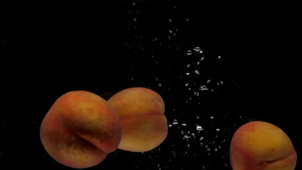 Slow Motion Three Peaches Falling Into Transparent Water on Black Background