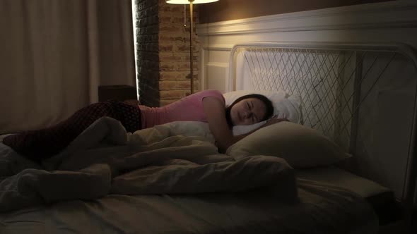 young girl in colored pajamas can not sleep at night in the bedroom.