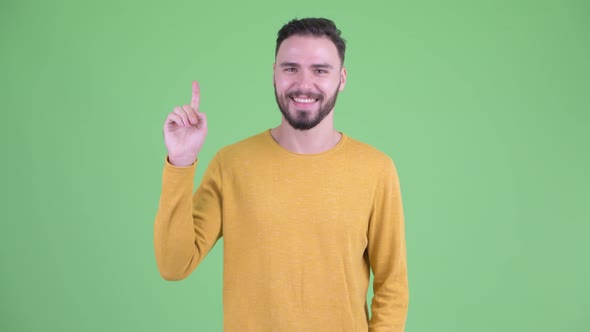 Happy Young Handsome Bearded Man Pointing Up