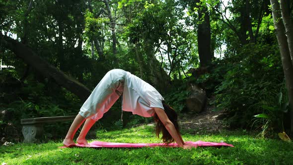 Mature woman performing yoga in the park 