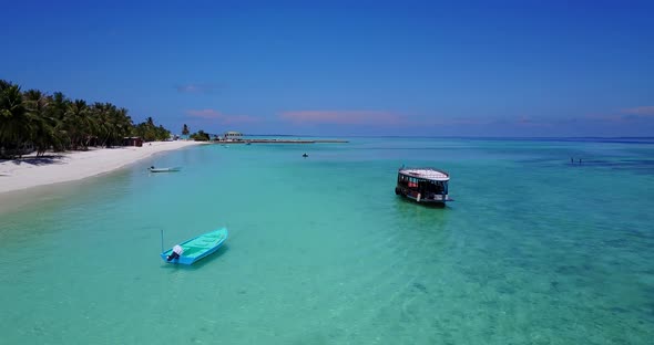 Wide angle birds eye island view of a paradise sunny white sand beach and aqua blue ocean background