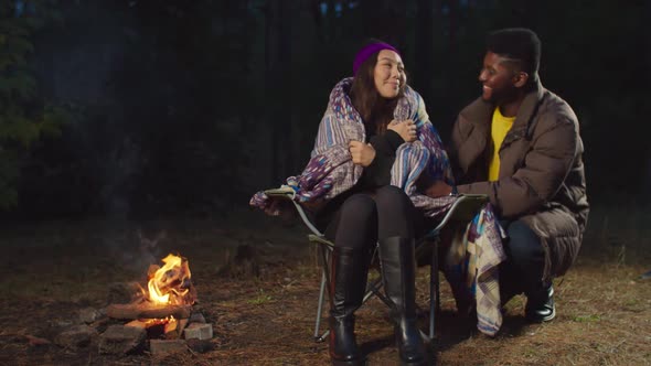 Man Covering Cold Woman with Blanket in Camping