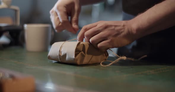 Male Artisan Wrapping Parcel on Table