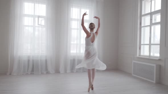 Graceful Ballerina Dancing and Tiptoeing in Pointe Shoes in a Bright Dance Class