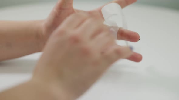Unrecognizable Woman Applying Medical Patch on Cut Finger at White Background