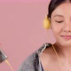 Happy pretty Asian teenager girl dancing and listening music by smartphone on pink background. - VideoHive Item for Sale