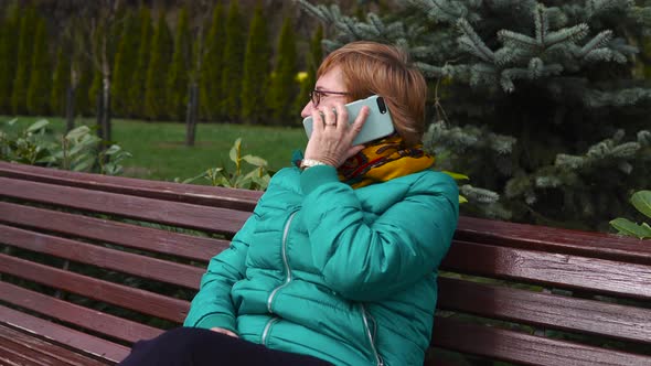 Senior Woman Talking on Mobile While Relaxing in the Park