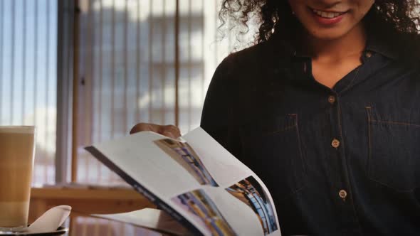 Woman reading magazine while having coffee