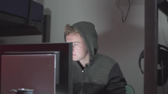 A left to right pan of a hacker at a computer.