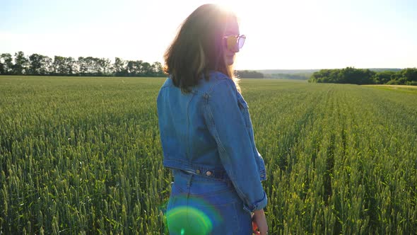 Attractive Brunette in Sunglasses Turning and Looking Into Camera. Young Smiling Girl Standing Among