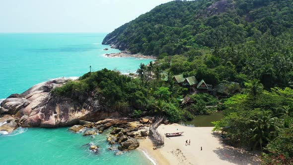Beautiful hidden beach with white sand, big cliffs crushed by sea waves on tropical island with gree