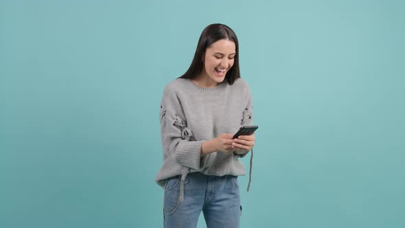 Young Happy Woman Using Smartphone. Excited Surprised Girl Texting on Her Phone.