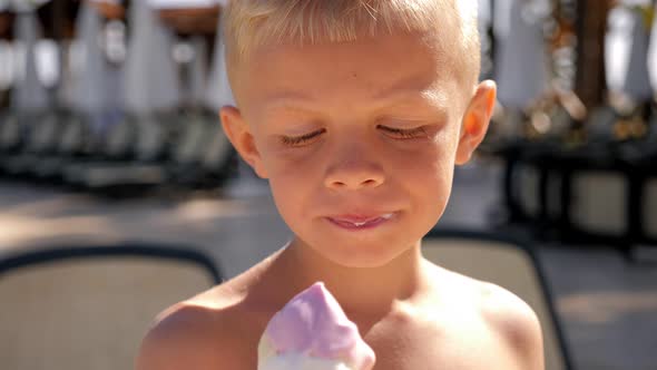 Closeup of a Boy of Eight Years Old Happily Eating Ice Cream By the Pool