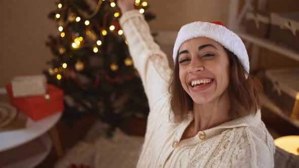 POV First Person View Happy Cheerful Excited Woman in Festive Santa Hat Taking Selfie on Background