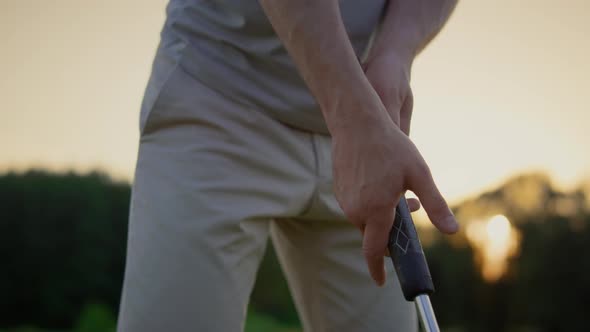 Professional Golf Player Hands Holding Club Putter on Sunset Fairway Field