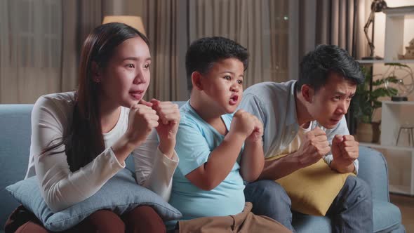 Excited Asian Family Watching Tv Together Sitting On A Sofa In The Living Room At Home