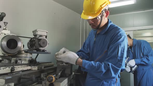 Asian mechanical technicians workers wear protective helmet and working on milling machine.