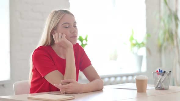 Tired Young Blonde Woman Sleeping while Sitting at Work