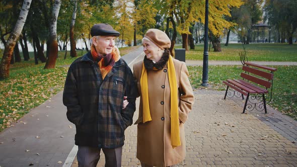 Happy Retired Spouses in Warm Elegant Outerwear are Talking and Smiling During Romantic Walk in City