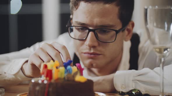 Closeup Face of Upset Caucasian Guy with Glasses Sitting Alone at Birthday Table at Home in Front of